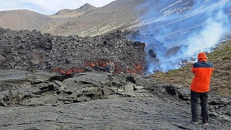 a person standing by a volcano explosion